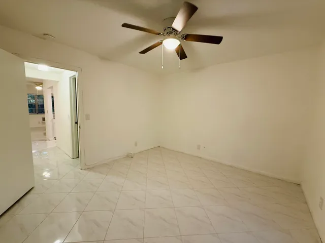 en empty room with ceiling fan and window