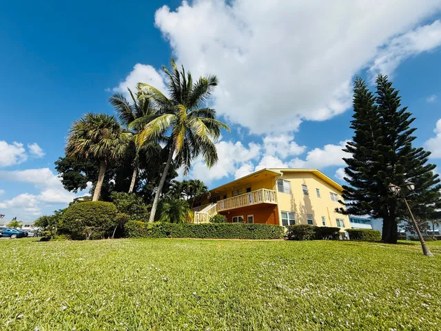 a view of a big house with a big yard and potted plants