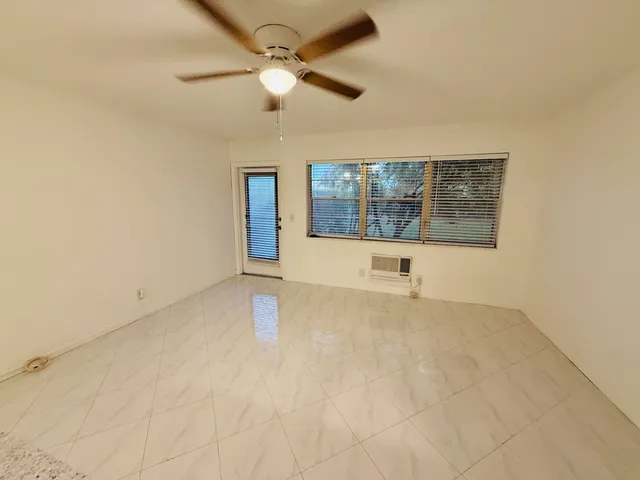 an empty room with windows and fan