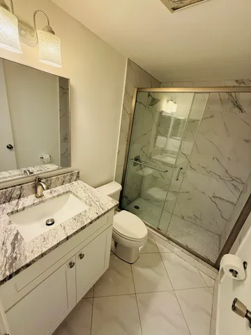 a bathroom with a granite countertop sink toilet and shower
