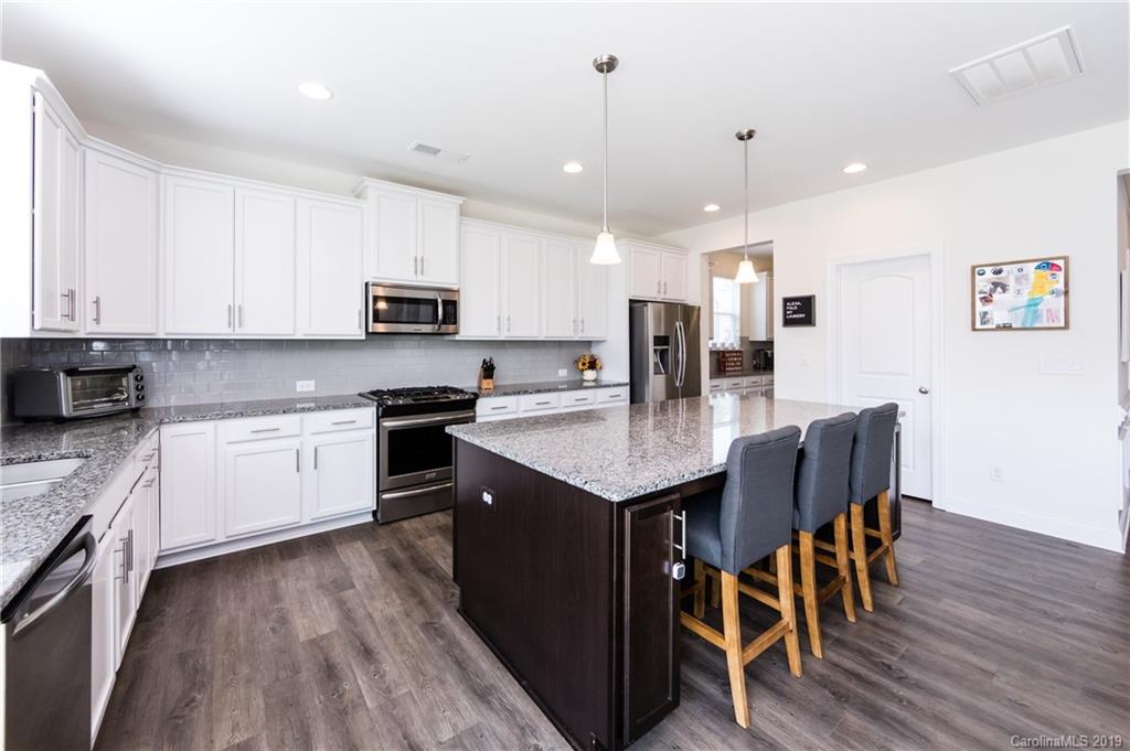 213 Morgan's Branch Road Belmont, NC 28012 - Photo 13 of 41 a kitchen with stainless steel appliances granite countertop a stove top oven a sink a dining table and chairs with wooden floor