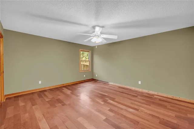 an empty room with wooden floor and windows with curtains