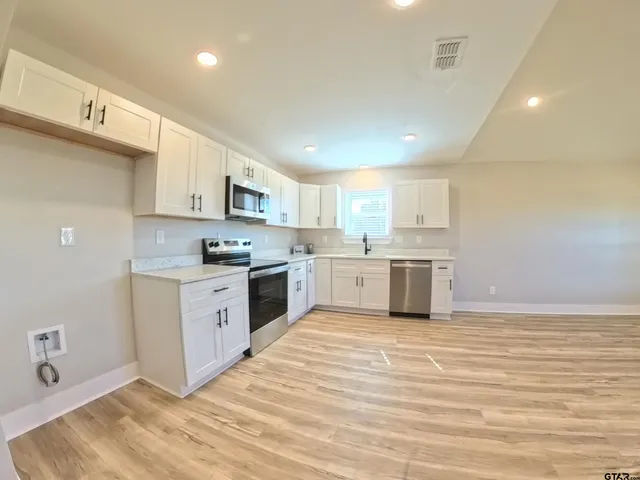 a large kitchen with a white stove top oven sink and cabinets