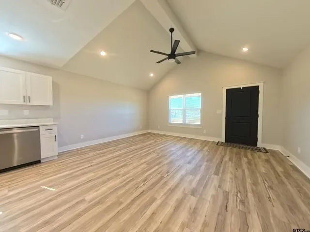 a view of empty room with wooden floor and fan