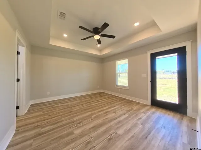an empty room with wooden floor a ceiling fan and windows
