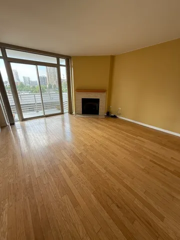 an empty room with wooden floor and a fireplace