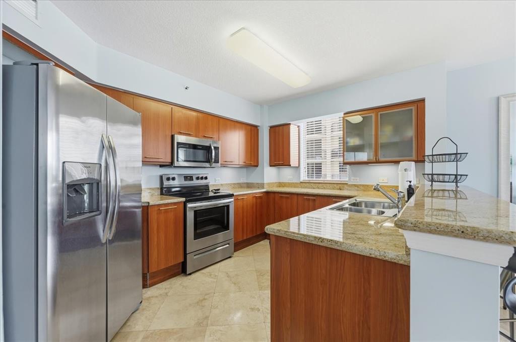 2011 North Ocean Boulevard, Unit 302 Fort Lauderdale, FL 33305 - Photo 14 of 45 a kitchen with stainless steel appliances granite countertop a refrigerator stove microwave and sink