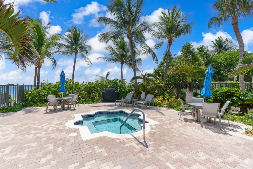 2011 North Ocean Boulevard, Unit 302 Fort Lauderdale, FL 33305 - Photo 42 of 45 a view of a patio with a table and chairs under palm trees