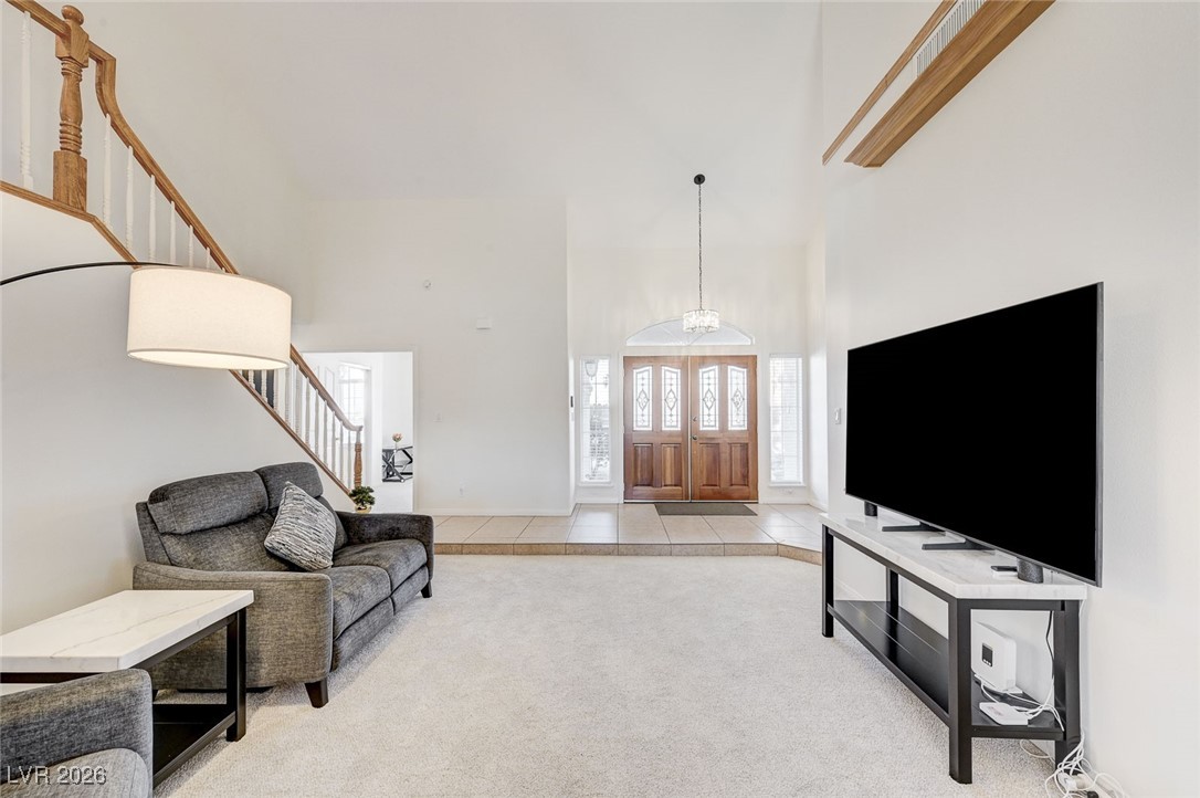 2955 El Camino Road Las Vegas, NV 89146 - Photo 39 of 99 Living area featuring a towering ceiling, light tile patterned floors, light carpet, and stairs