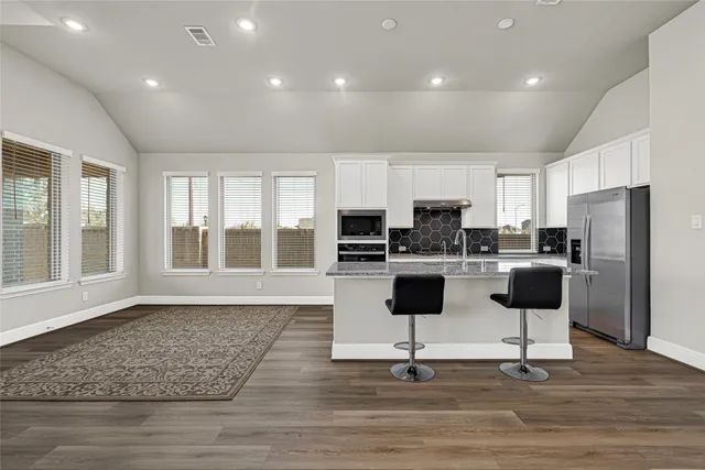 a kitchen with stainless steel appliances granite countertop a refrigerator and a stove top oven