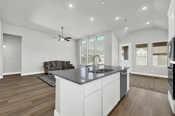 a kitchen with center island wooden floor and a sink