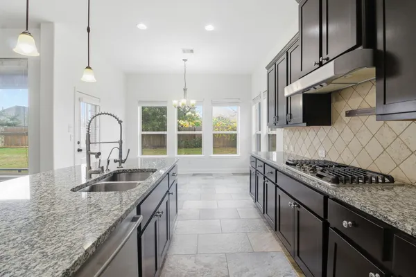 a kitchen with granite countertop sink stove and cabinets