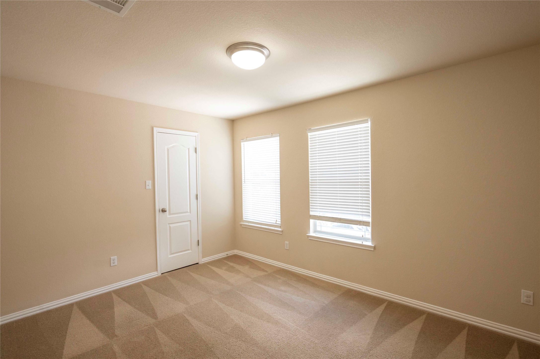 2070 Intrepid Drive Buda, TX 78610 - Photo 25 of 31 A well-lit bedroom features plush carpeting and multiple windows.