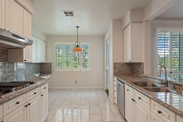 a kitchen with granite countertop a sink stove and cabinets