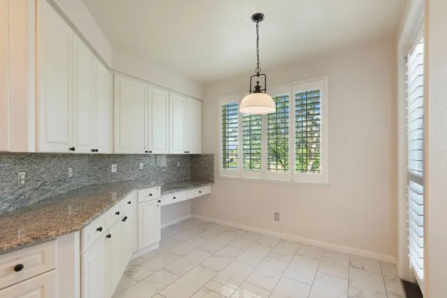 a kitchen with white cabinets and window