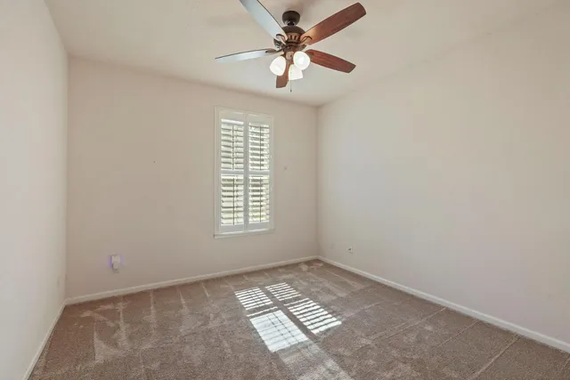 an empty room with a window and a fan