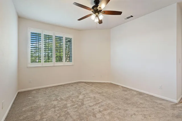 an empty room with a window and a fan
