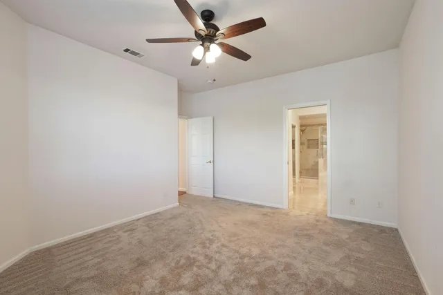 an empty room with a chandelier fan and windows