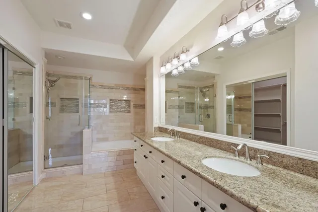 a bathroom with a granite countertop double vanity and a mirror