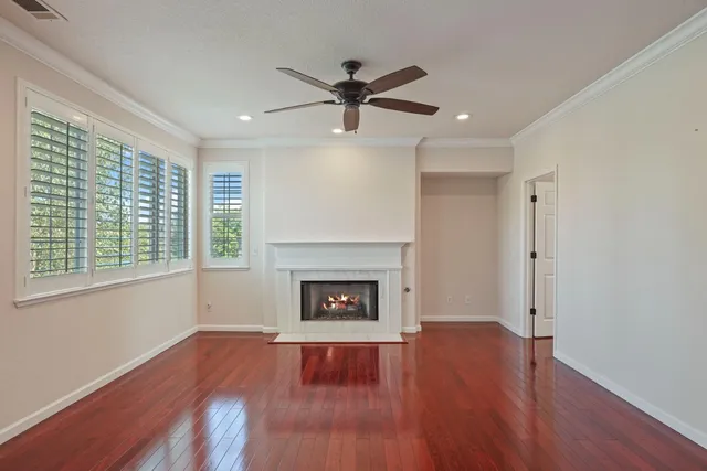 an empty room with wooden floor fireplace and windows