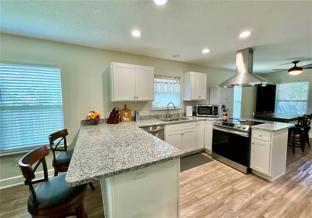 a kitchen with stainless steel appliances kitchen island granite countertop a sink stove and refrigerator