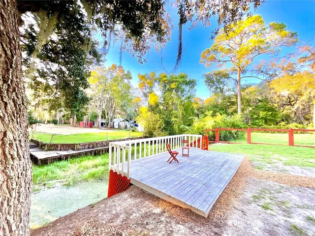 a view of a backyard with large trees and wooden fence
