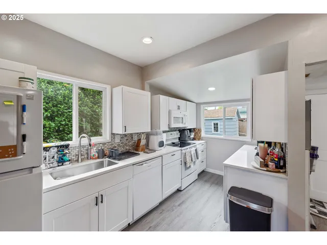 a kitchen with white cabinets a sink dishwasher and a fireplace with wooden floor