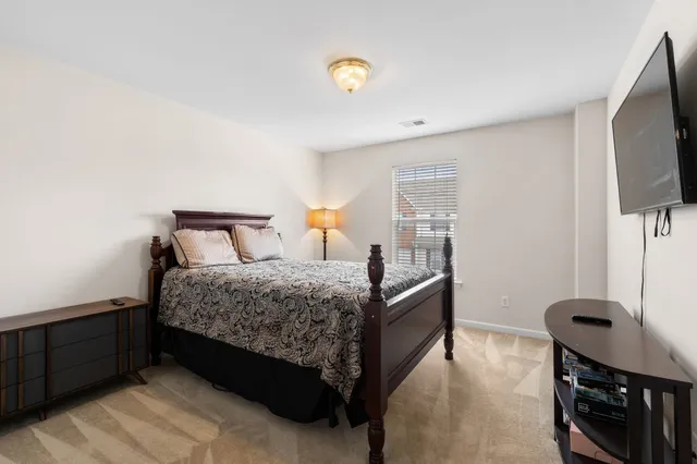 a bedroom with a bed and a flat tv screen on a dresser