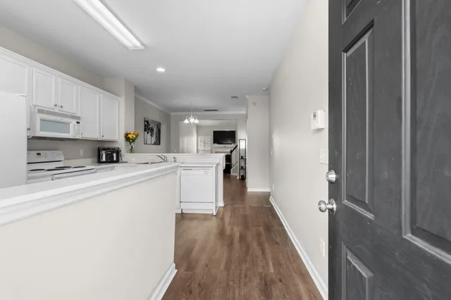 a white kitchen with wooden floor and stainless steel appliances