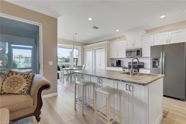 a kitchen with stainless steel appliances granite countertop a table chairs refrigerator and a sink