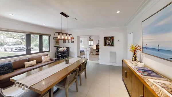 a view of a dining room and livingroom with furniture wooden floor a rug a flat screen tv a painting and a chandelier