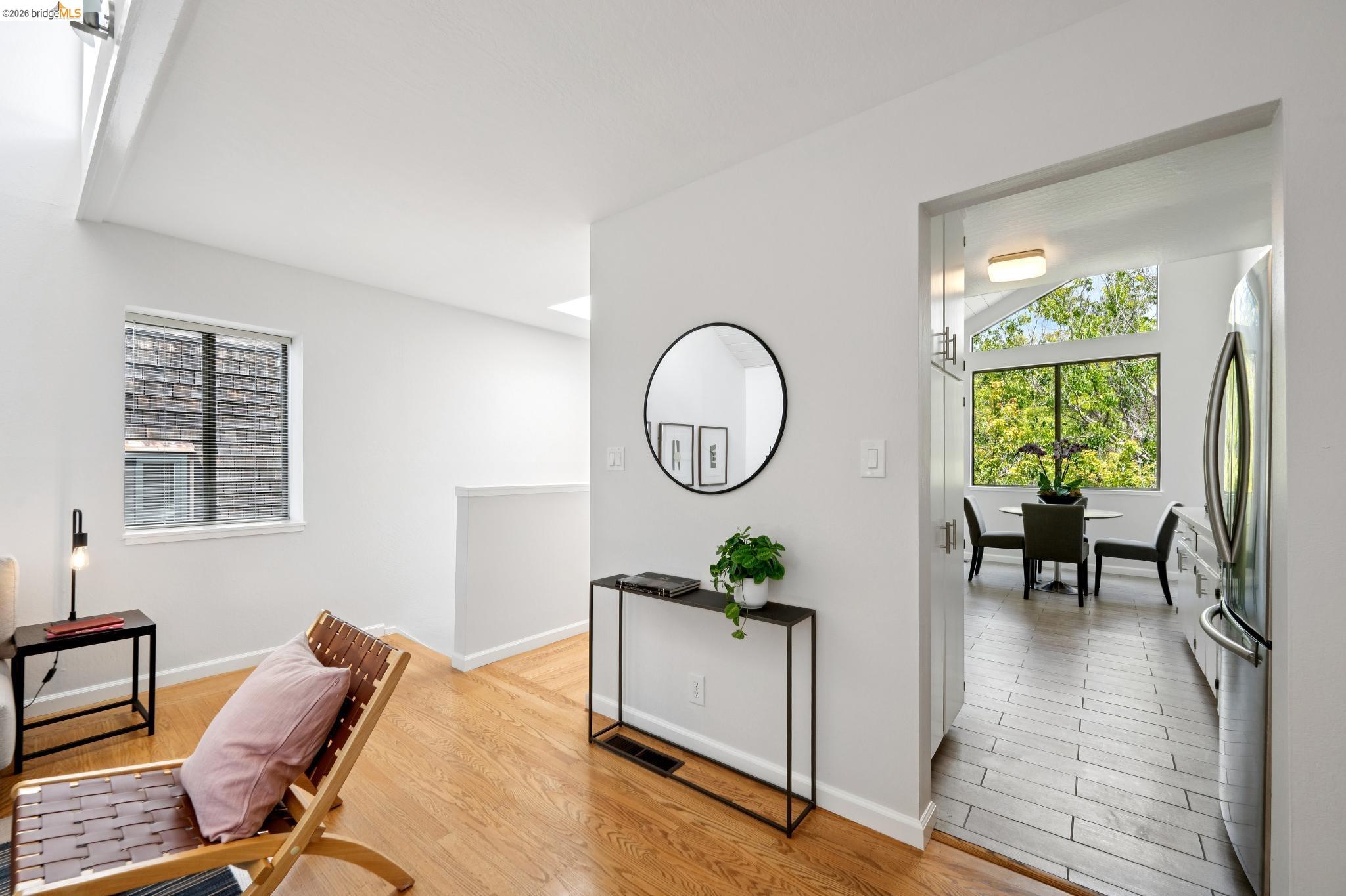 1340 Henry Street Berkeley, CA 94709 - Photo 17 of 52 Bright interior with wood-finish flooring, a white-painted half-wall, and a black-framed circular mirror