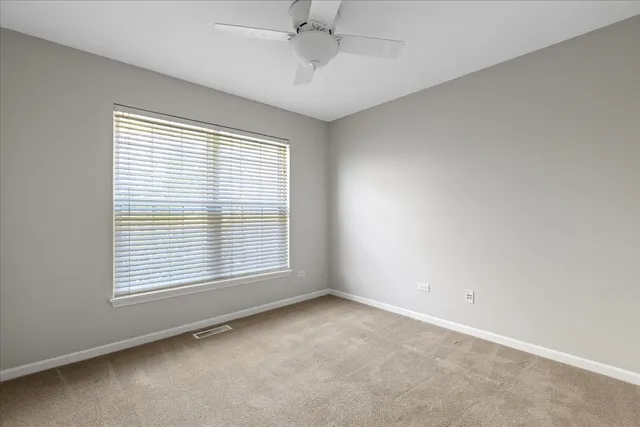 an empty room with a window and a ceiling fan