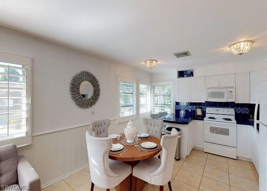 151 Mandalay Road Fort Myers Beach, FL 33931 - Photo 14 of 32 a kitchen with a dining table chairs and white cabinets