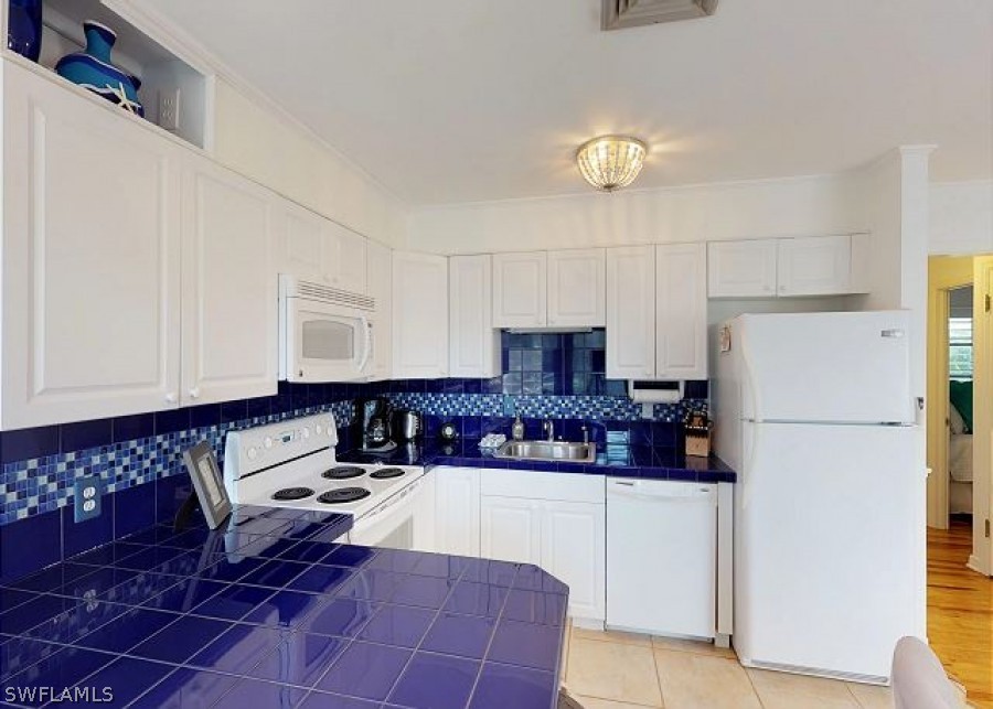 151 Mandalay Road Fort Myers Beach, FL 33931 - Photo 15 of 32 a kitchen with stainless steel appliances granite countertop a refrigerator sink and white cabinets
