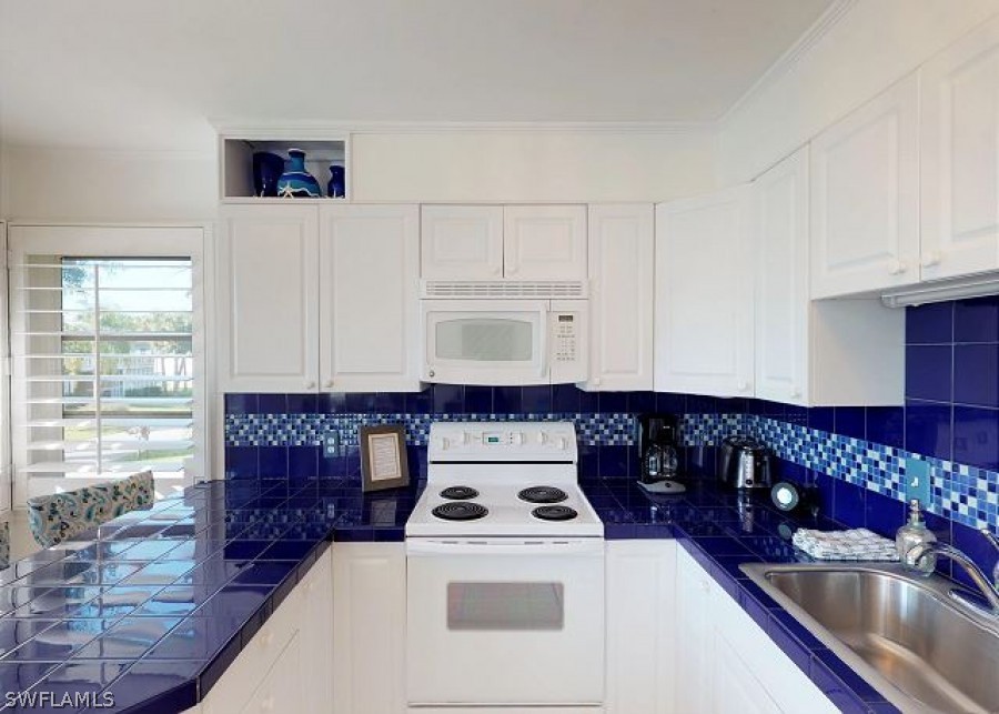 151 Mandalay Road Fort Myers Beach, FL 33931 - Photo 16 of 32 a kitchen with a stove a refrigerator and a sink with wooden floor