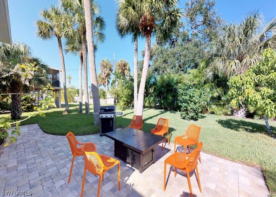 151 Mandalay Road Fort Myers Beach, FL 33931 - Photo 25 of 32 a view of a patio with table and chairs potted plants and palm trees