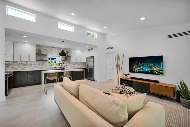 a living room with stainless steel appliances furniture and a flat screen tv