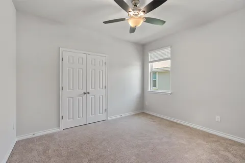 en empty room with a ceiling fan and carpet