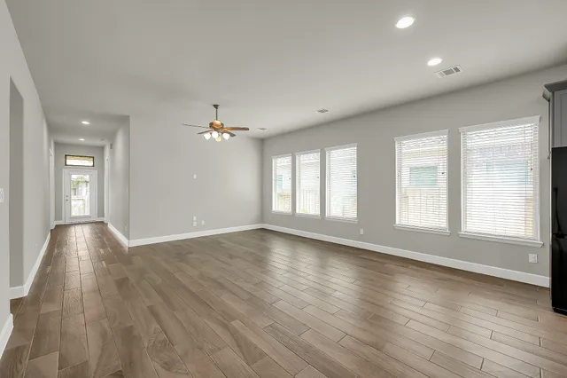 a view of an empty room with wooden floor and a window