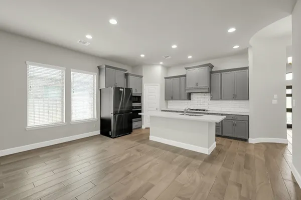 a kitchen with stainless steel appliances kitchen island granite countertop a refrigerator and a stove top oven