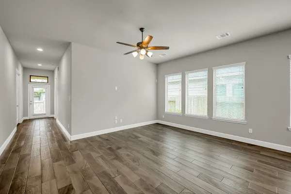 a view of an empty room with window and wooden floor