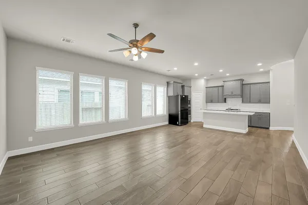 a view of an empty room with a kitchen and a window