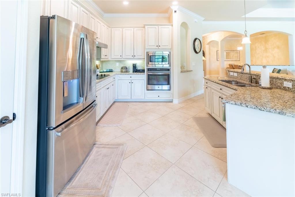9372 Vercelli Court Naples, FL 34113 - Photo 11 of 50 Kitchen with appliances with stainless steel finishes, light stone countertops, light tile patterned floors, ornamental molding, and sink