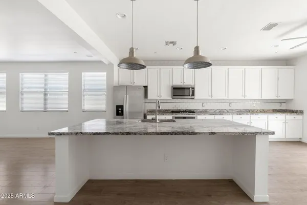 a kitchen with granite countertop a sink stainless steel appliances and white cabinets