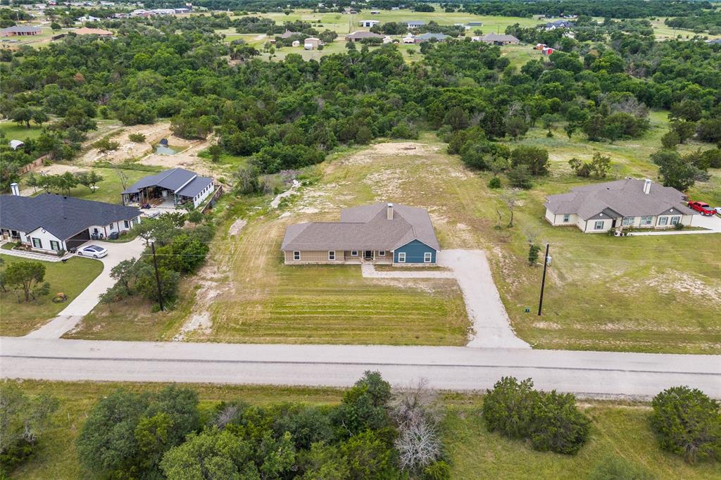 139 Kriston Lane Springtown, TX 76082 - Photo 35 of 39 Single-story residence featuring a combination of blue siding and neutral-toned stone veneer, set on an expansive lot with a gravel driveway