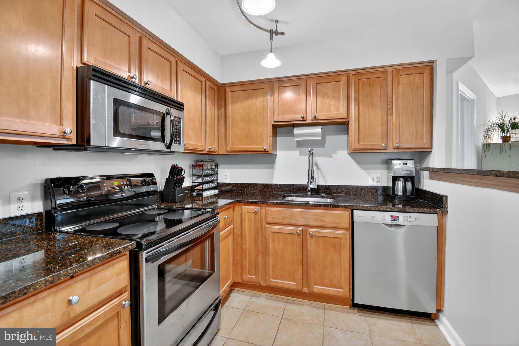 1001 North Vermont Street, Unit 102 Arlington, VA 22201 - Photo 6 of 27 a kitchen with stainless steel appliances granite countertop a stove a sink and a microwave