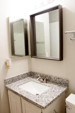 a bathroom with a granite countertop sink and a mirror