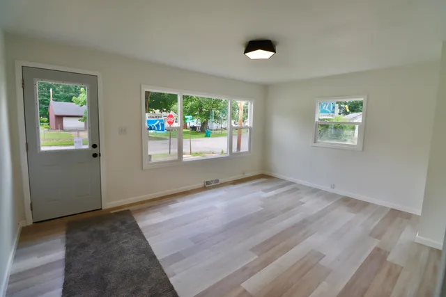 an empty room with wooden floor and windows