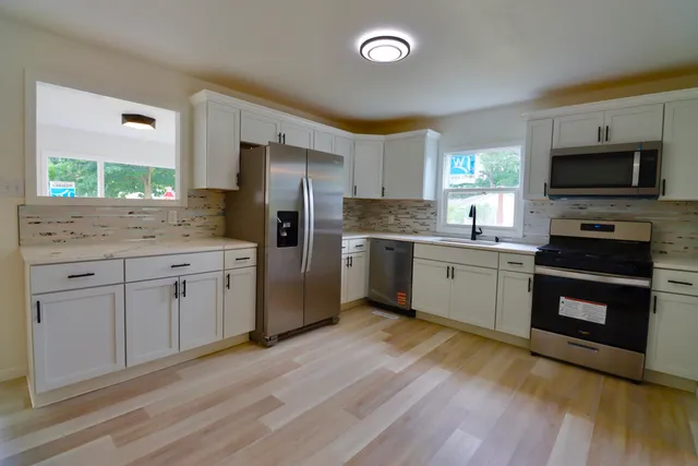 a kitchen with a sink cabinets stainless steel appliances and wooden floor